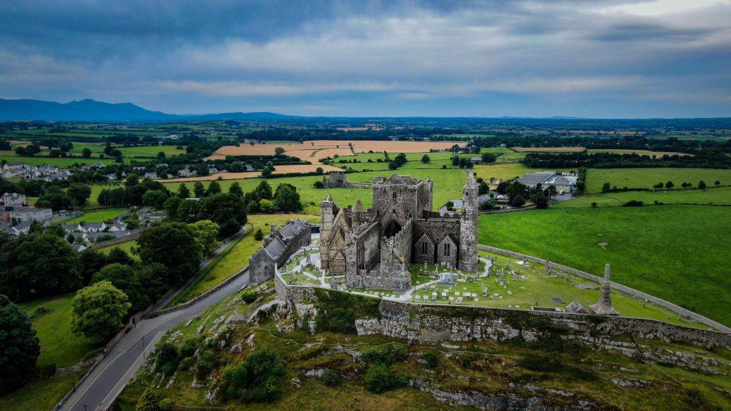 Rock of Cashel against green fields and a cloudy sky, County Tipperary, Ireland